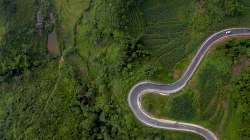 Top down shot of a motorcycle on a winding road in the lush green mountains of northern Vietnam. Ma