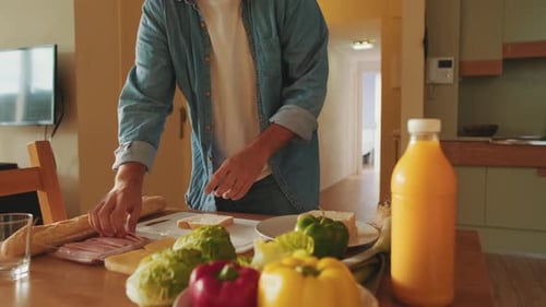 Young Adult Making Sandwich at Kitchen Table
