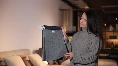 Woman Inspecting Gray Fabric Swatches in Showroom