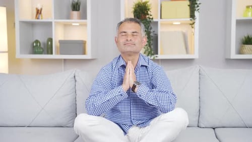 Calm Mature Adult Meditating on Couch