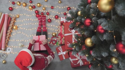 Wrapping Christmas Present on Floor Next to Christmas Tree
