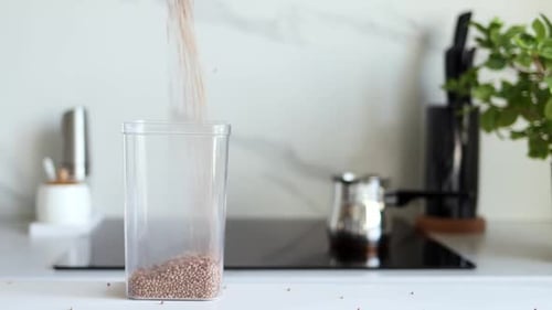 Buckwheat Grains Being Poured into Container on Countertop