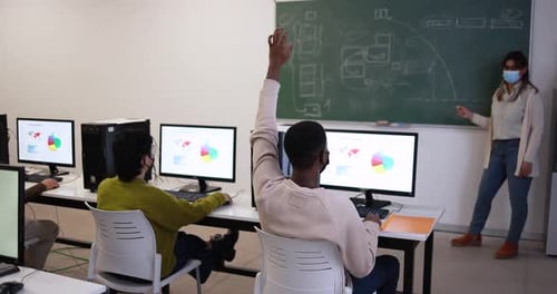 Young Multiracial Students and Teacher Wearing Safety Face Masks Inside Computer Class