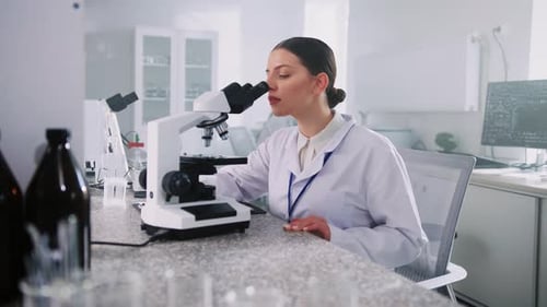 Scientist Examining Samples Under a Microscope in Lab