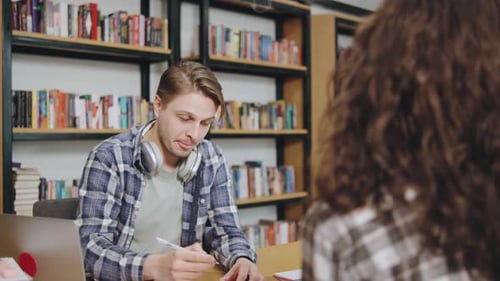 Engaging Conversation Between a Young Man and Woman in a Library Setting During the Day Discussing