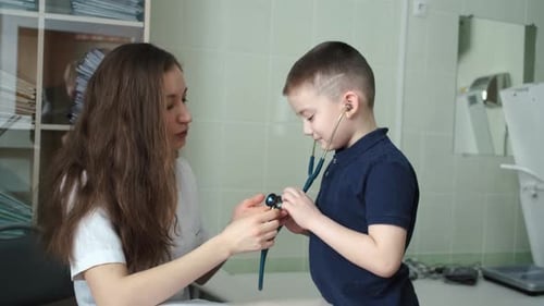 a boy listens to how a stethoscope works at a doctor's appointment