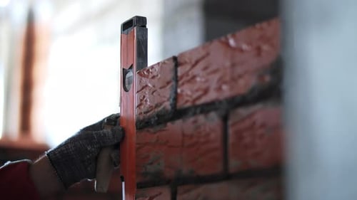 Bricklayer Checking Brick Wall Alignment with Spirit Level