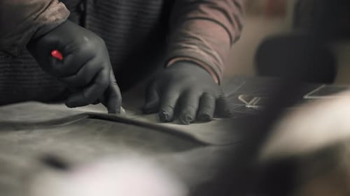 Craftsperson Cutting Leather on Table with Sharp Knife