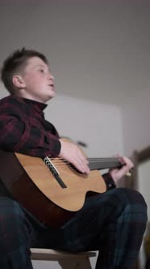 Teen Boy Plays Guitar Indoors Portrait