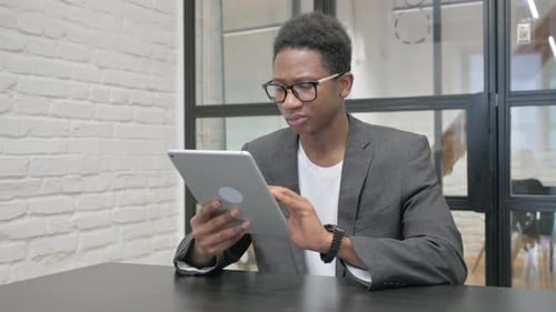 Young African Man Using Digital Tablet in Office