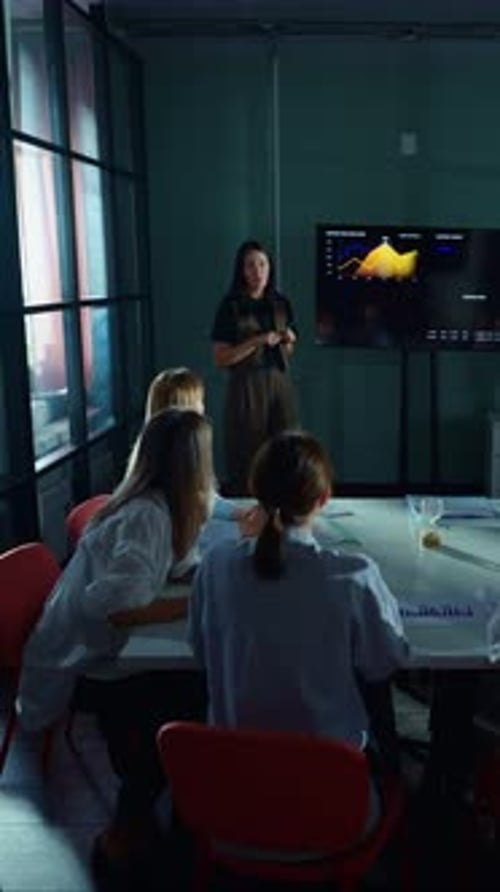Businesswoman Giving Datadriven Presentation to Colleagues in Modern Office Meeting Room Explaining