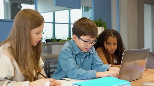 Group Of Elementary School Children Working Together On Laptop In Class