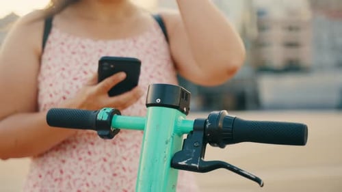 Woman Rents Electric Scooter Using Mobile Phone App at the Street