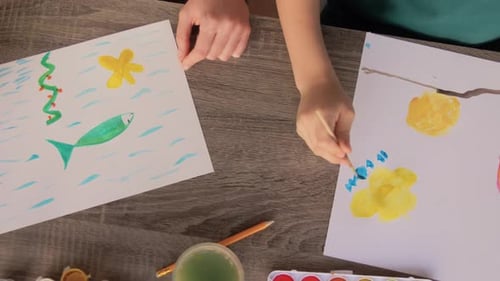Child and Woman Painting Pictures Together at Table