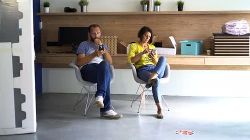 Man and Woman Relaxing, Using Smartphones at Home