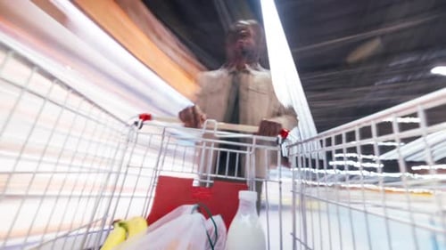 Time Lapse of African American Man Walking in Supermarket Shopping for Food Putting Products in Cart