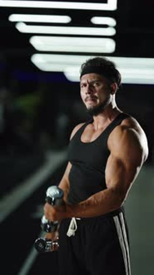 Focused Athlete Performing Dumbbell Curls in a Modern Gym Highlighting Sculpted Biceps Powerful