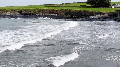 Strong waves on the beach in Ireland west coast - Irish landscape in the background