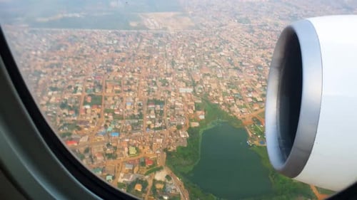 View through airplane window over the city during landing on cloudy day.