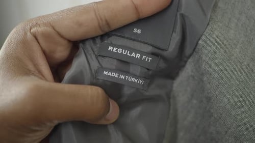 Etiquetas de ropa exhibidas a mano que destacan el corte regular y el origen en Turquía