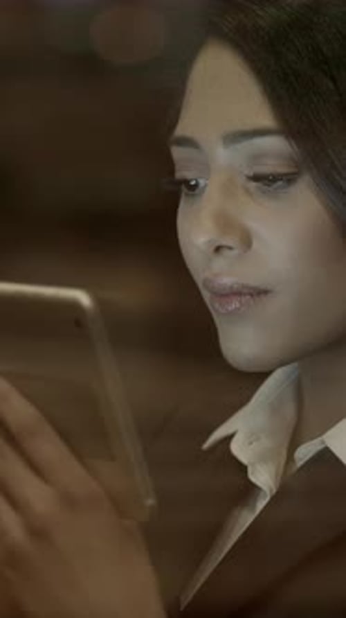 A Focused Professional Woman is Engaged Intently with a Tablet Device in Her Workspace