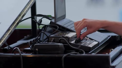 Un Primer Plano Detallado de la Mano de un Músico Interactuando con Varios Equipos Electrónicos | Clip