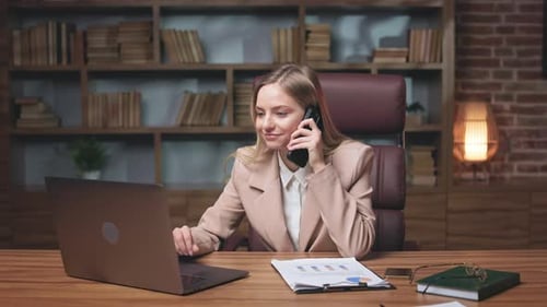 Woman Working at Desk While Talking on Phone