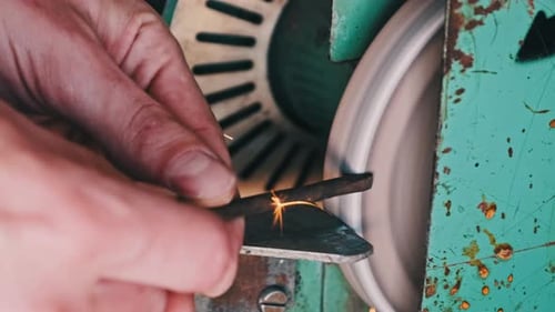 Hands of a Craftsman Working on an Abrasive Wheel in a Workshop