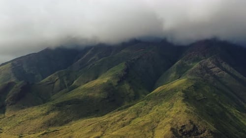 Dark dense clouds covering idyllic mountains of Maui, Hawaii. Aerial wide shot.