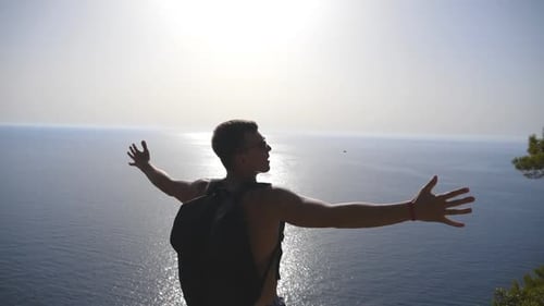 Man Reaches Top of Cliff Overlooking Ocean