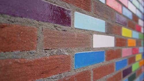 Brightly colored bricks pattern a red brick exterior wall of a building