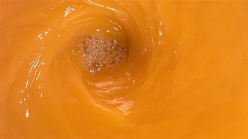 Peaches Splashing into Refreshing Orange Juice Vortex