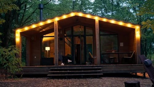 large beautiful wooden house in the forest with large windows and glowing lanterns for holiday