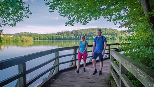 Couple walking wooden hiking trail along beautiful lake, slow motion