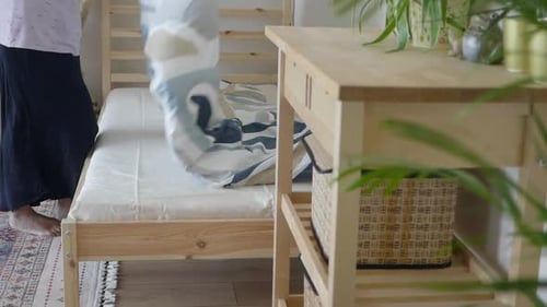 Woman Making Bed in Bright, Modern Bedroom