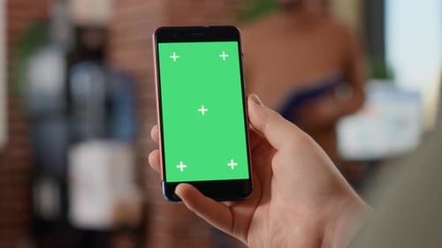 Hand Holding Phone with Green Screen in Office