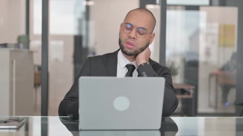 Young Adult Massaging Neck in Modern Office