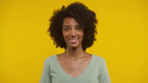 Smiling Woman with Curly Hair Posing on Yellow Background