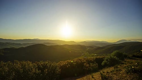 Timelapse shot of sun setting over mountain range during evening time.