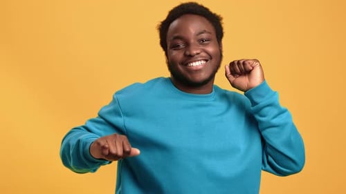 Portrait Smiling Afro Young Man Dancing with Positive Emotion Posing Isolated on Orange Studio