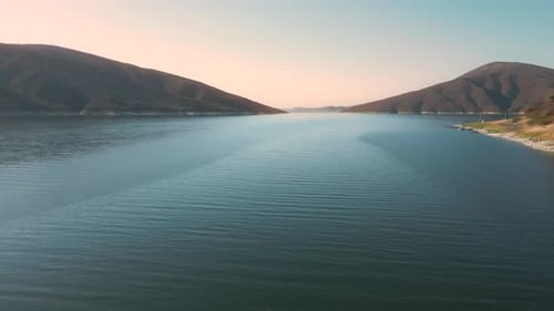 Aerial drone flying over a lake, water dam, with mountains at sunrise. Beautifull dreamy landscape v