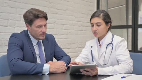 Doctor Explains Diagnosis to Patient Using Tablet