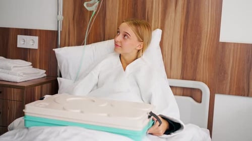 A girl lying in a hospital room is brought tray with delicious food to strengthen her strength