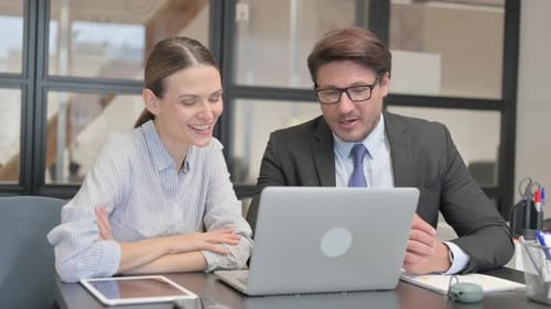 Business Colleagues Reviewing Laptop Together in Office