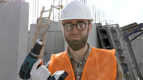 Repairman worker in uniform and helmet holding cordless screwdriver, standing on his workplace