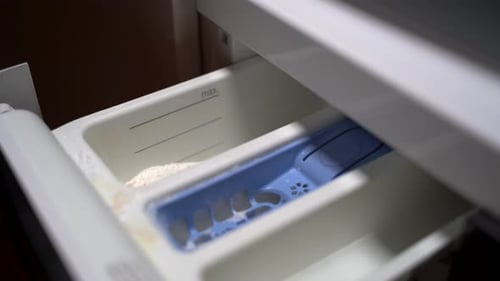 Young woman putting detergent into the washing machine 4K