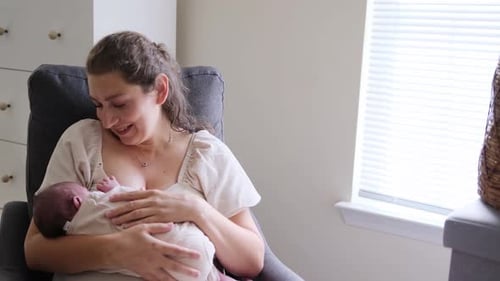 Mother Holding Newborn Infant in Gray Armchair