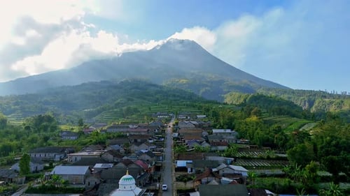 Drohne fliegen über ein Dorfhaus am Berghang mit der Kulisse des aktiven Merapi-Vulkans