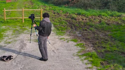 Adult Adjusting Camera on Tripod in Rural Setting