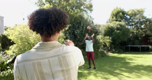 Two Men Throwing Football in Backyard During Daytime